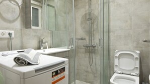A modern bathroom with a glass-enclosed shower, a toilet, and a washing machine. - Koukaki Gem Cozy 1BR Renovated Apt near Center (Athina)