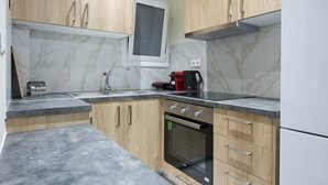 A modern kitchen with wooden cabinets, a built-in oven, and a stainless steel refrigerator. - Koukaki Gem Cozy 1BR Renovated Apt near Center (Athina)