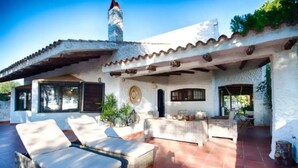 Una casa con un patio que incluye dos tumbonas y una zona de estar cubierta.