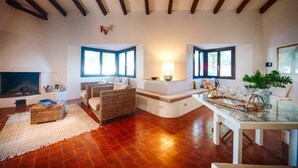 Un salón amplio con chimenea, asientos cómodos y ventanas grandes.