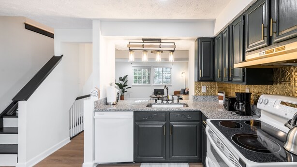 Una cucina moderna con mobili scuri, un piano cottura bianco e un ripiano in granito.