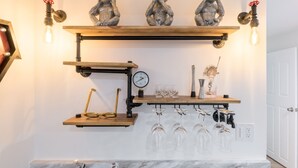 Una cucina con uno scaffale in legno che contiene tre statue, un manometro e una cantina con bicchieri.
