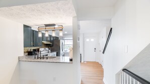 Una cucina moderna con piani in granito, elettrodomestici in acciaio inossidabile e illuminazione a sospensione.