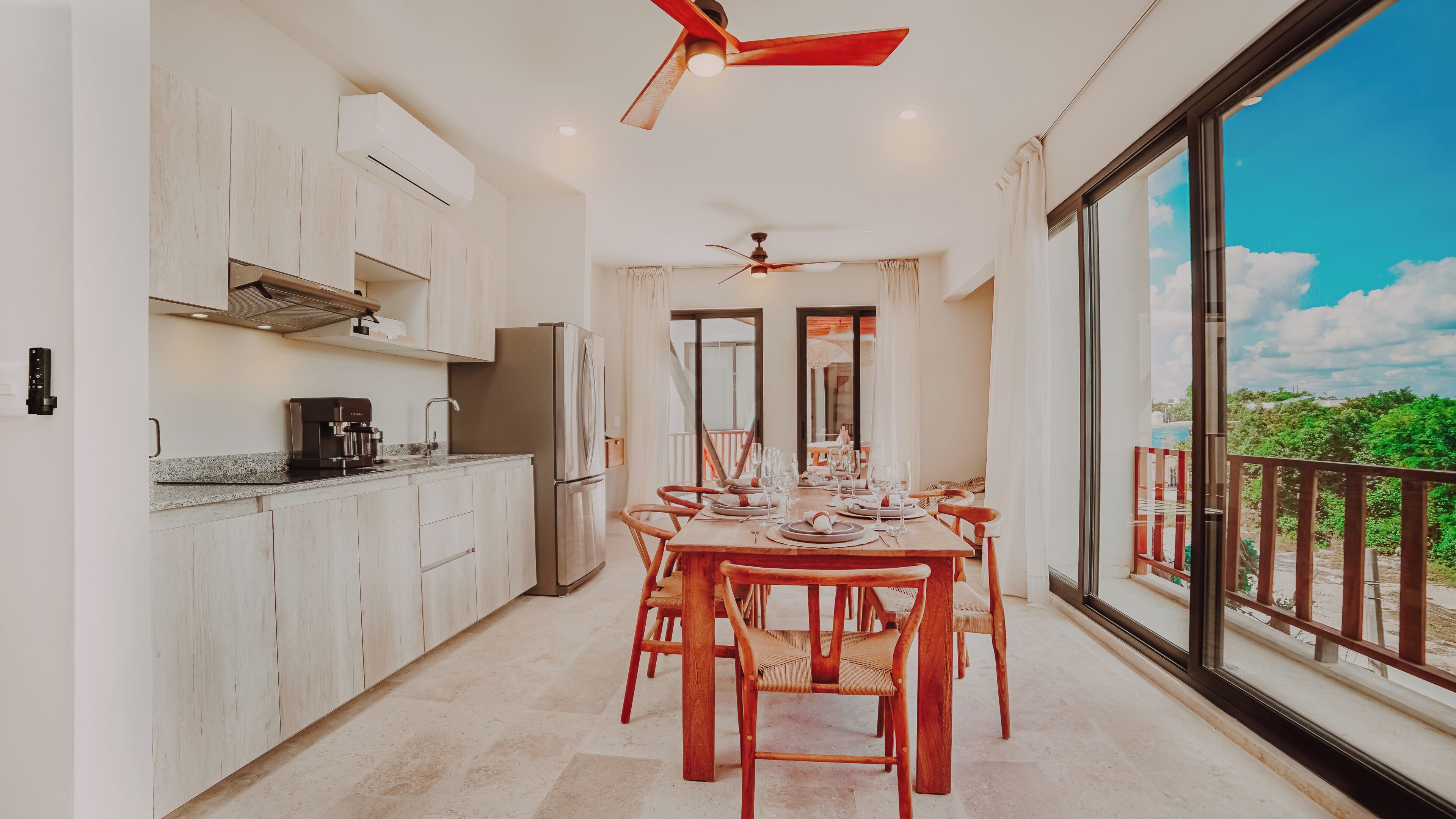 A modern kitchen with a dining area, large windows, and a balcony.