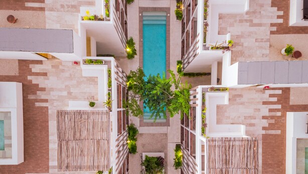 A modern hotel with a central pool, multiple balconies, and lush greenery. - Smart Depas Tulum (Tulum)