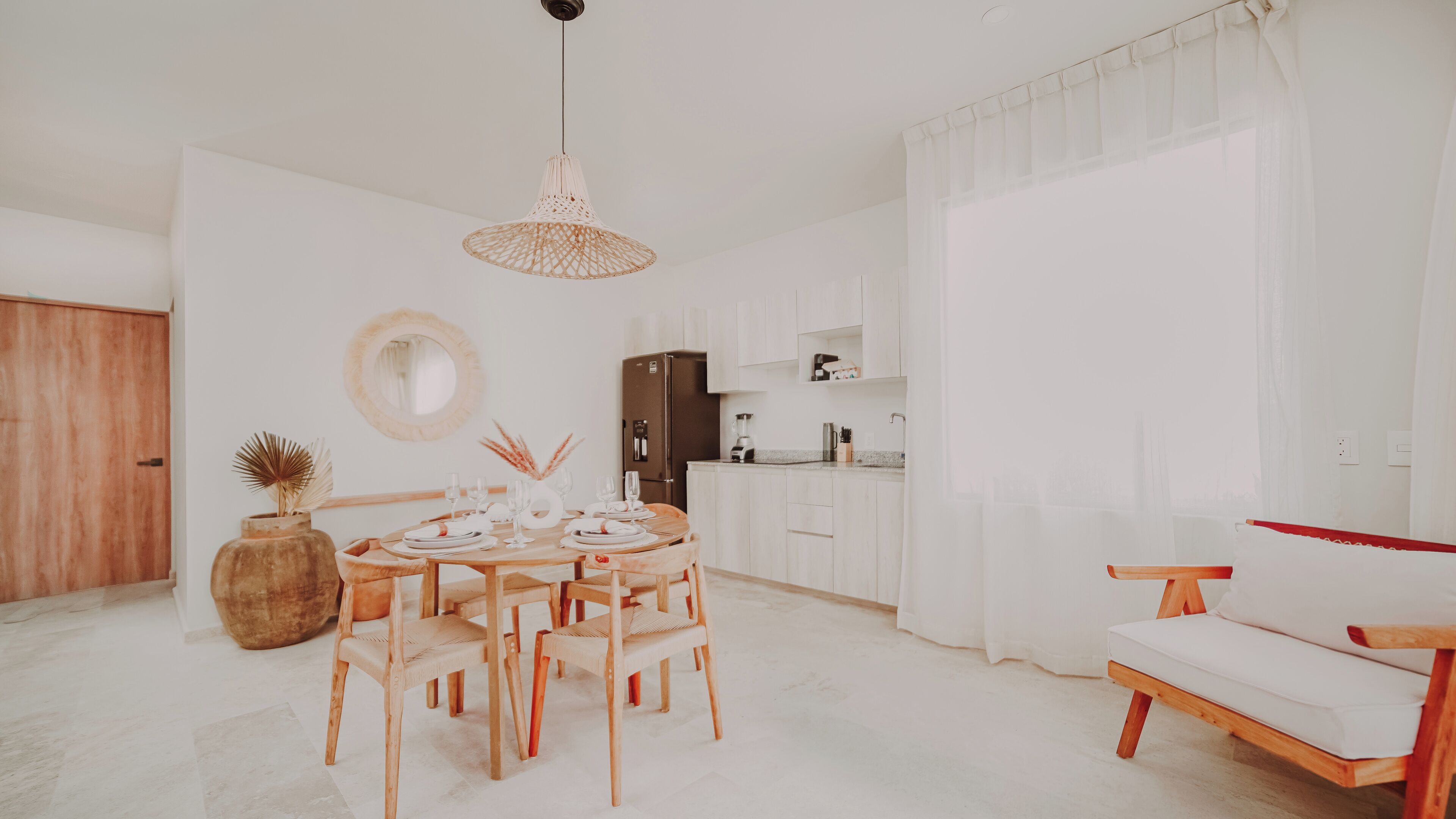 Une cuisine moderne avec des meubles blancs, une table à manger pour quatre personnes et un banc en bois.
