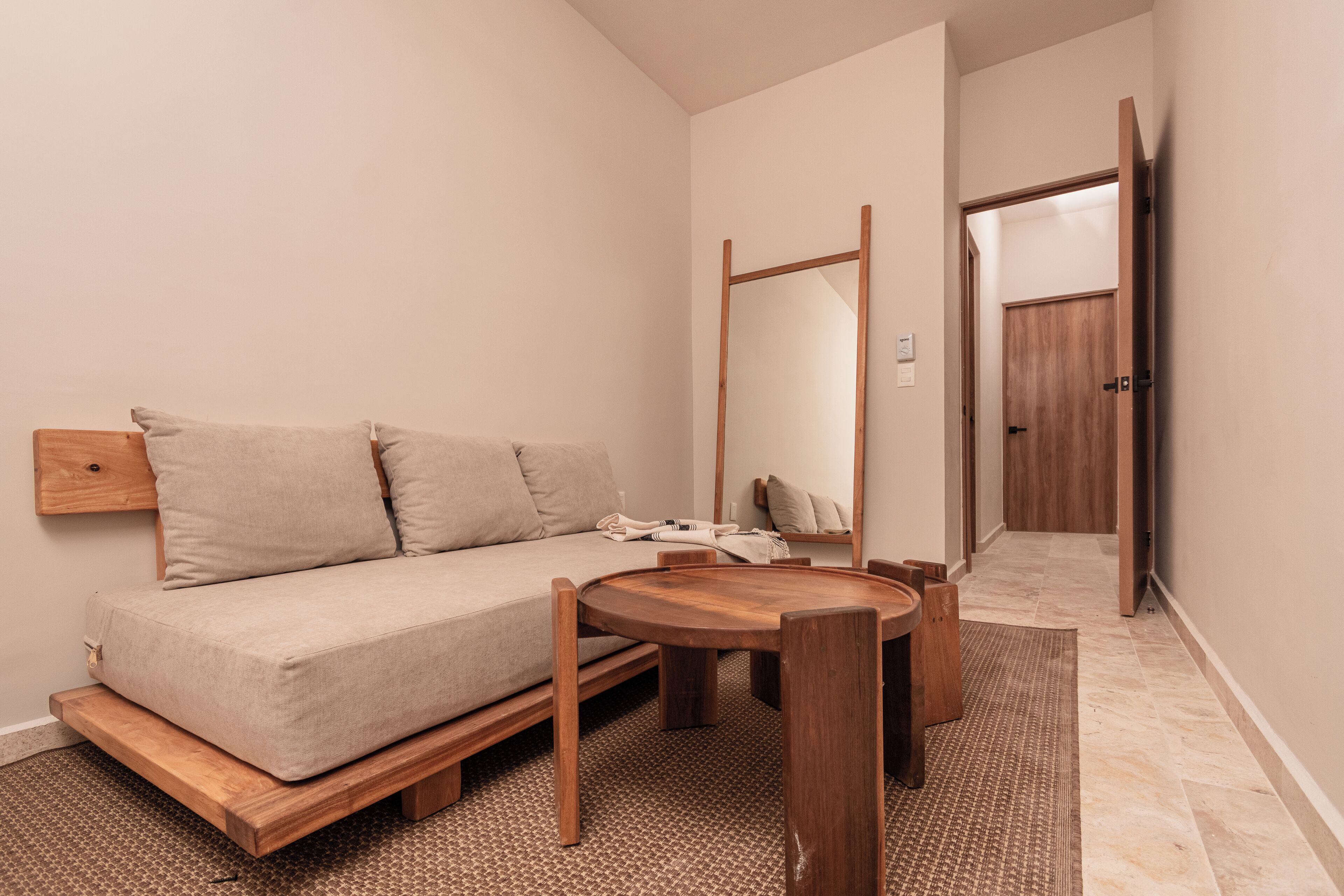 A minimalist room with a sofa, a wooden table, and a mirror.