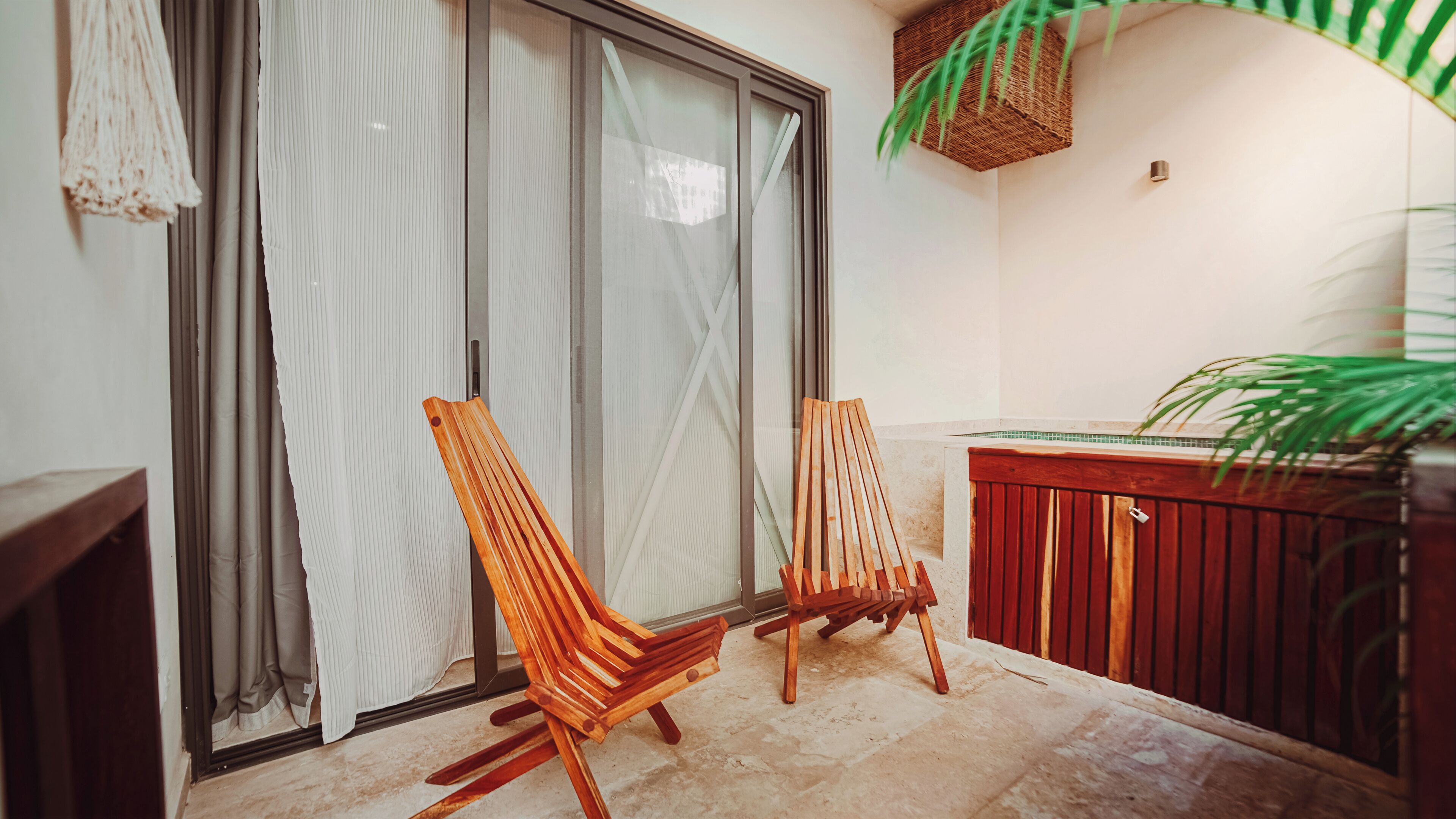 Un balcón con dos sillas de madera, un banco rojo y una planta en maceta.