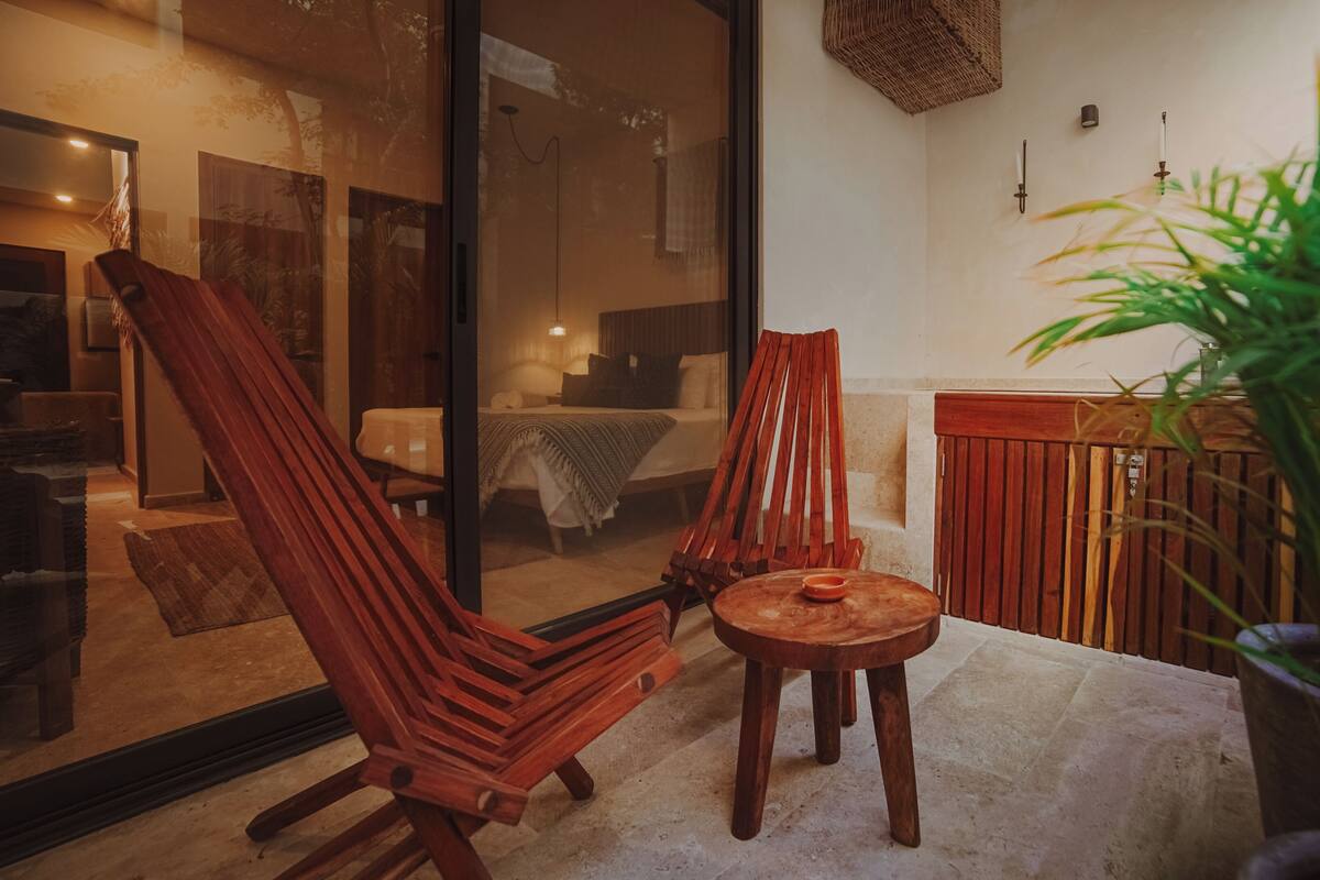 A room with two wooden chairs, a small round table, and a potted plant.