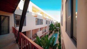 A hotel with multiple balconies, a swimming pool, and a clear sky.
