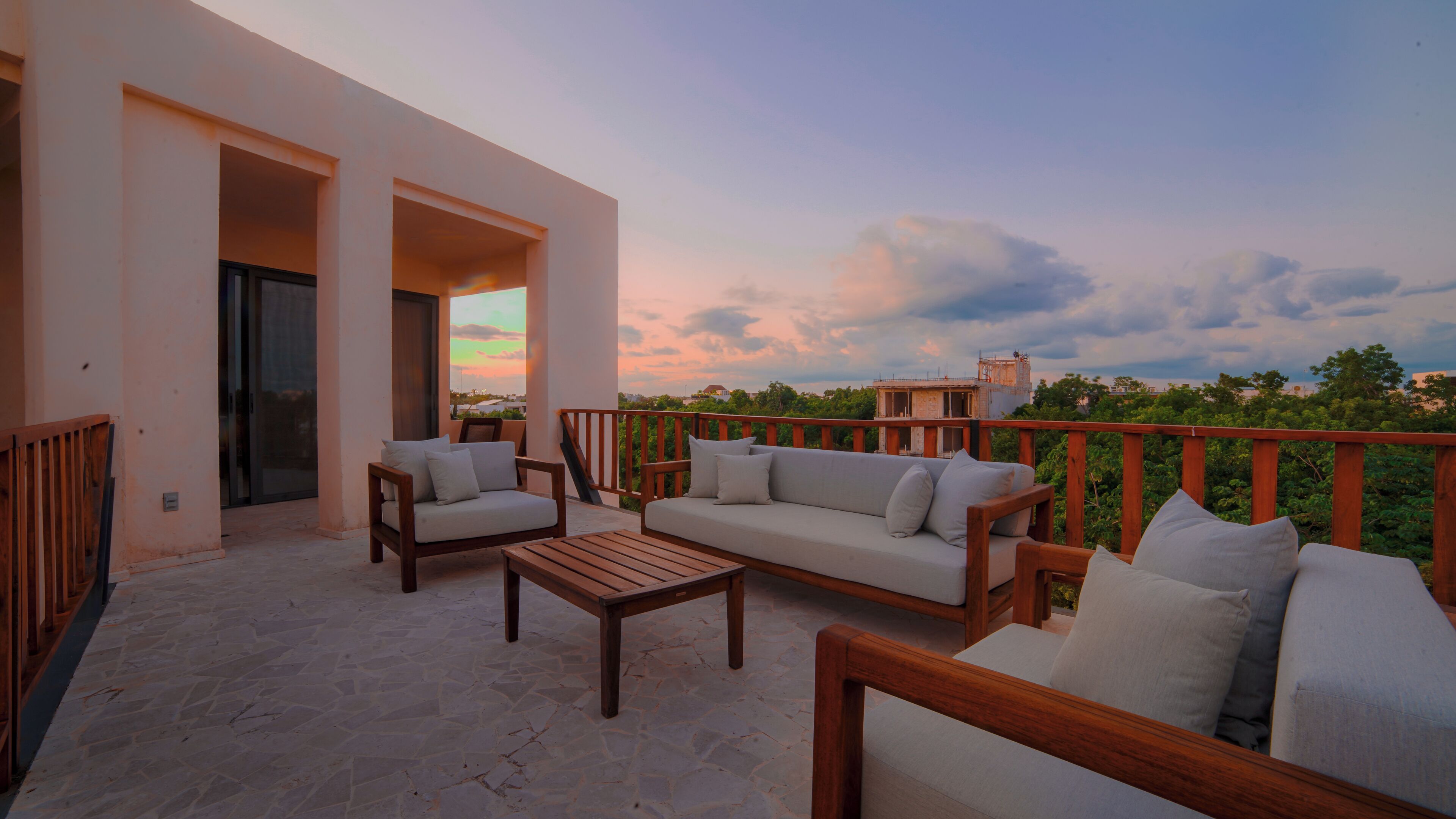 A balcony with a sofa, chairs, and a table.