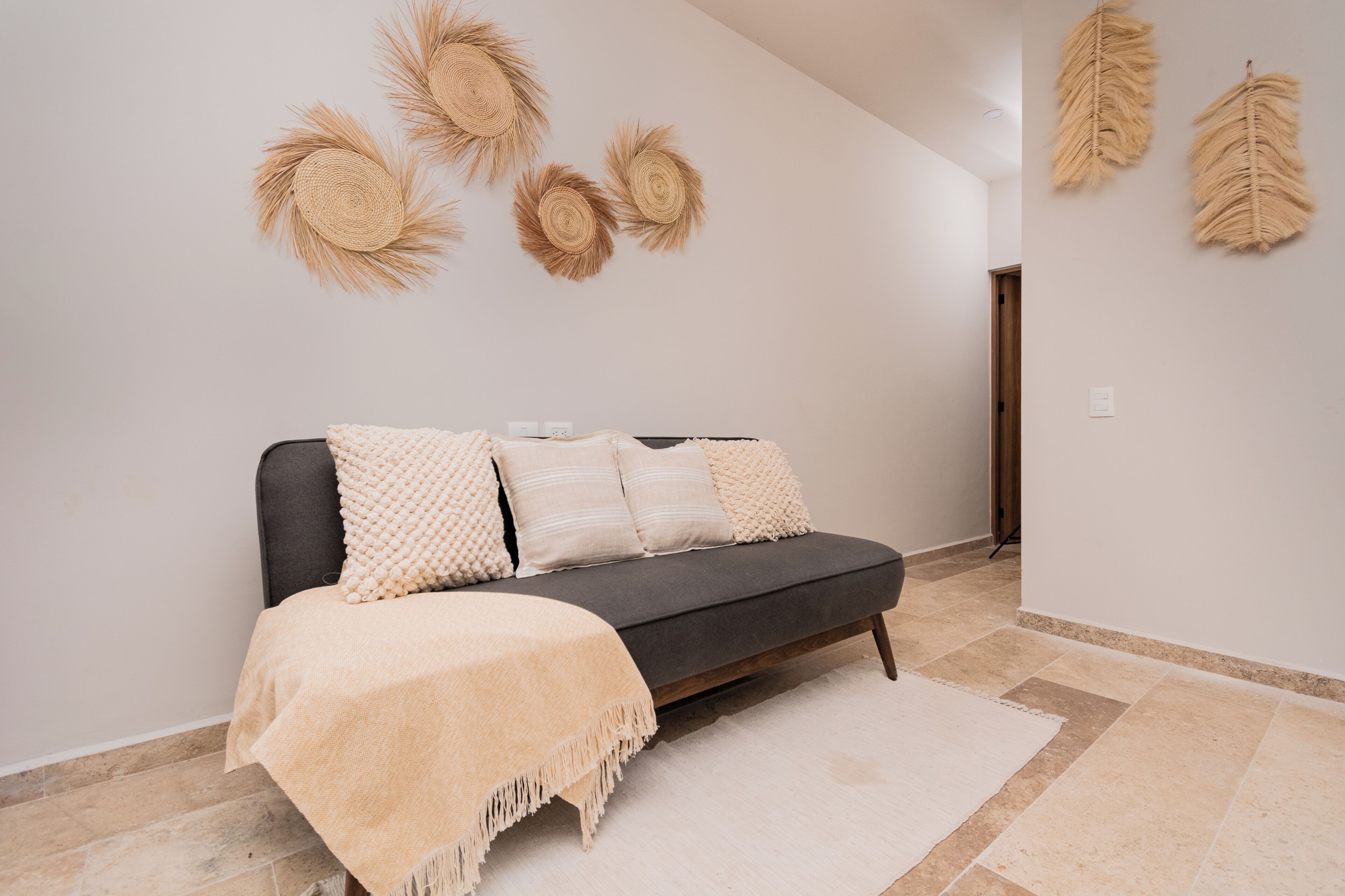 Una sala moderna con un sofá, decoración en la pared y una paleta de colores neutros.
