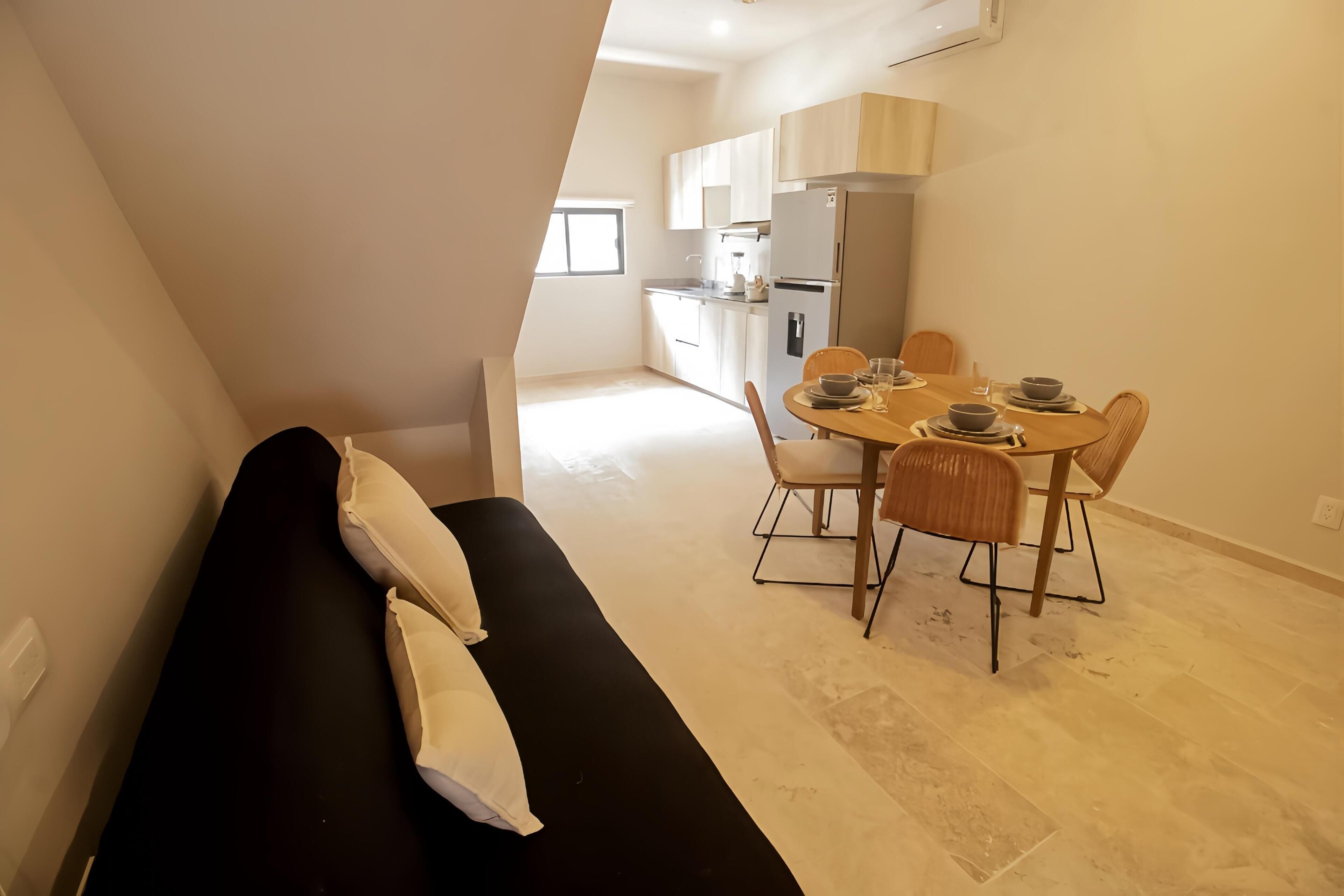 A modern interior with a dining area, a bench, and a kitchen in the background.