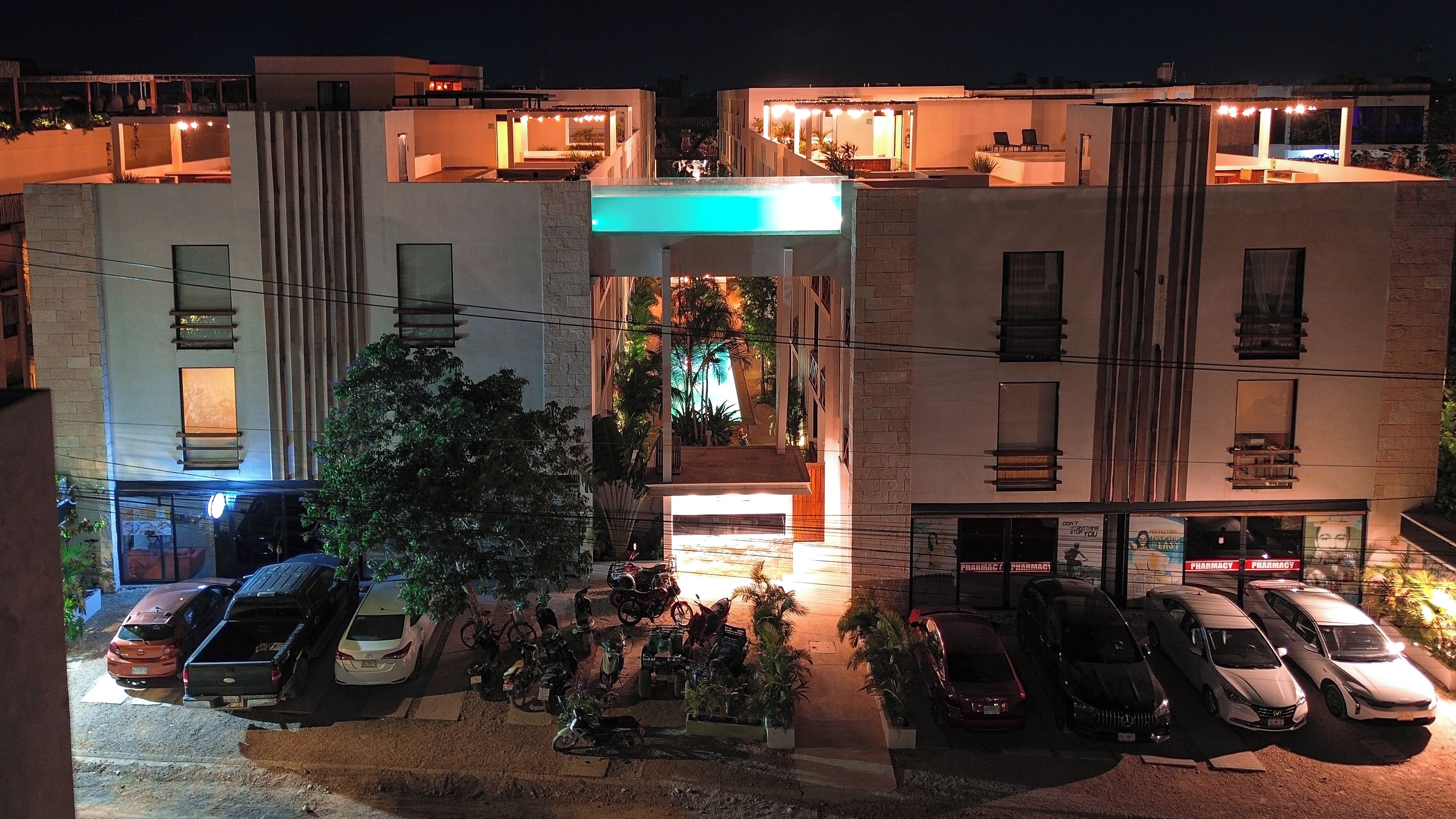 A multi-story building with a central courtyard, outdoor seating, and a pharmacy on the ground floor.