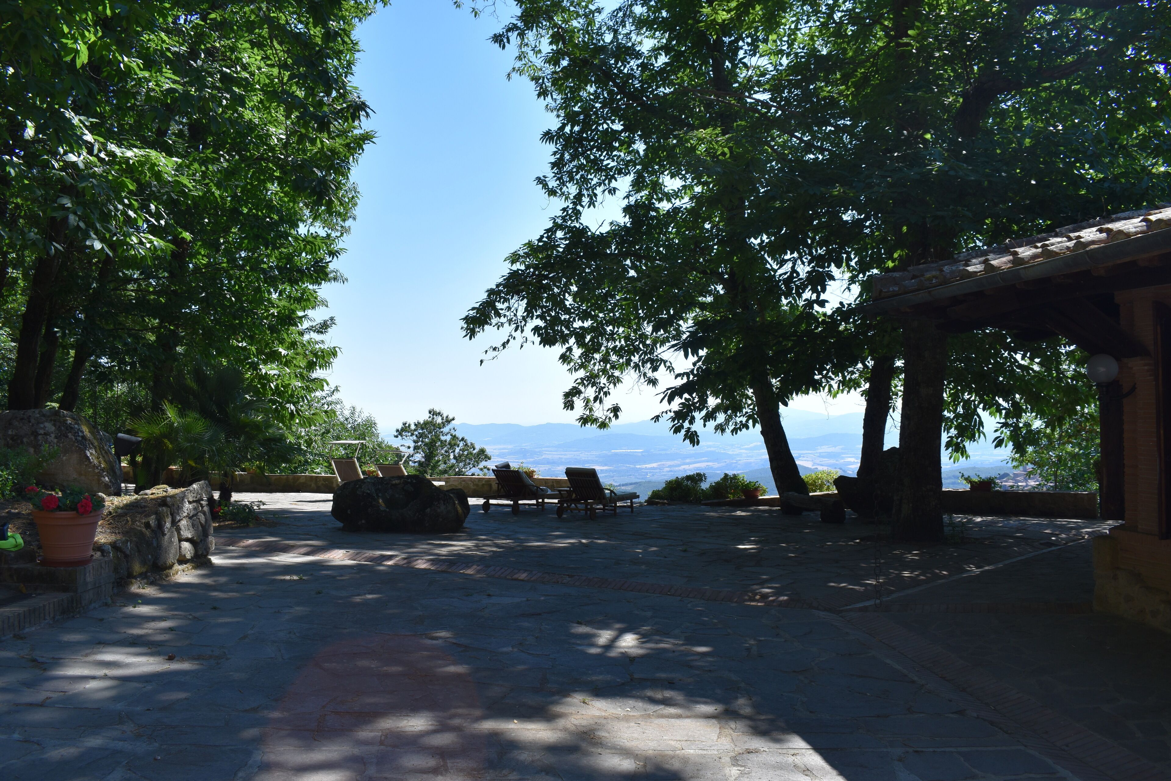 An outdoor patio area with stone flooring, lounge chairs, and a view of the mountains.