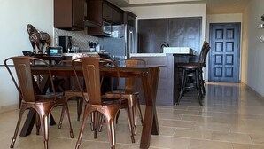 A spacious kitchen with modern appliances, a dining area with a large table and chairs, and a separate dining counter. - CONDO Q BY TRVL2HM (Cabo San Lucas)