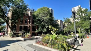 A public square with a brick building, a fountain, and a street lamp.