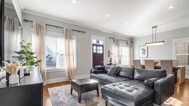 A modern living room with a sectional sofa, a coffee table, and a dining area with chairs. - Pet Friendly Large House | 10 Min to Broadway (Nashville)