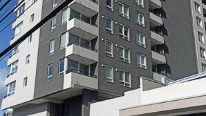A multi-story residential building with balconies, a ground-level entrance, and a closed garage door labeled "SALA". - Apartamentos Bauerle (Temuco)