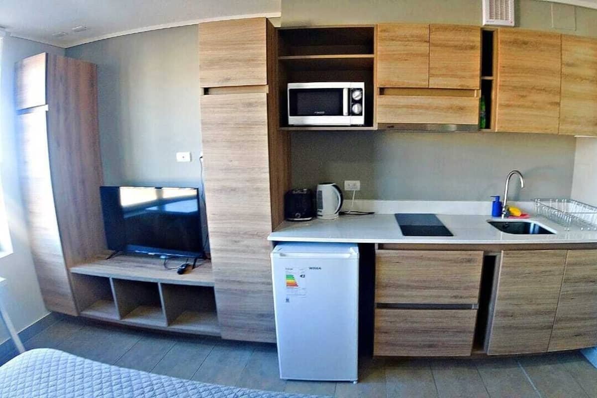 Cocina compacta con microondas, tostadora y refrigerador.