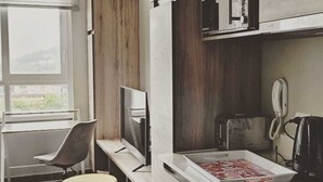 A modern kitchen with a built-in microwave, a coffee maker, and a phone on the counter. - Apartamentos Bauerle (Temuco)