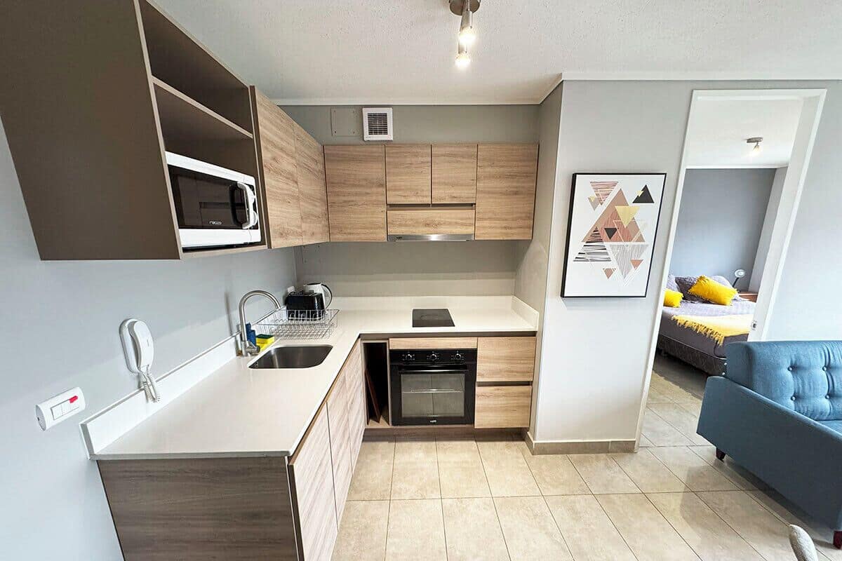 Una cocina compacta con electrodomésticos integrados, un lavamanos y una zona de comedor.