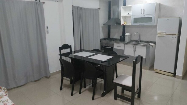 A compact kitchen with a dining area, a refrigerator, and a stove.