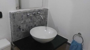 A small bathroom with a white sink, a mirror, and a towel ring.