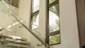 A modern staircase with glass railings and a wooden door. - Perfectly located in Playa Guiones. Walk to the beach, shops, restaurants & yoga (Nosara)