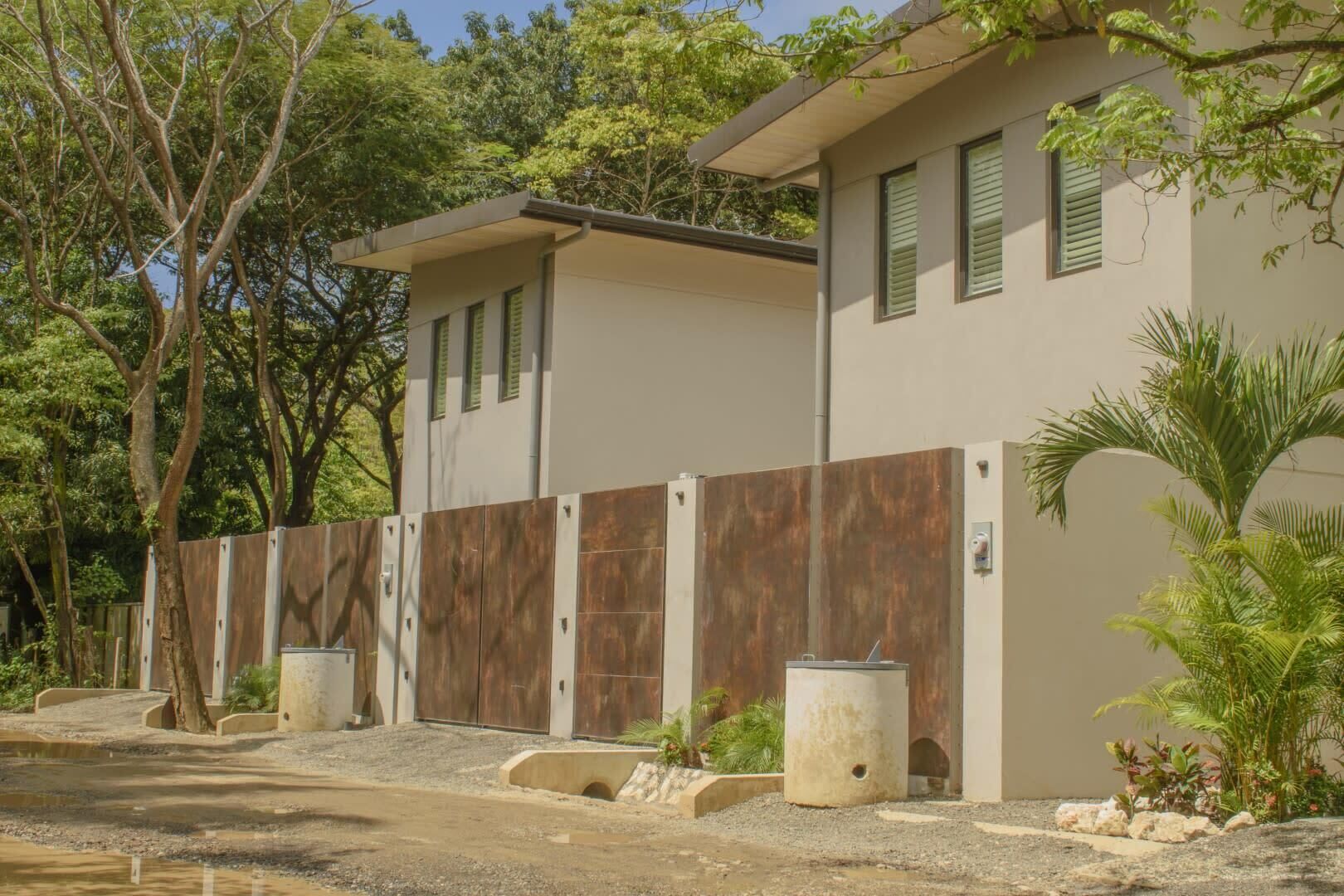 Edifici modern de dues plantes amb façana beix, persianes verdes i tanca de fusta.