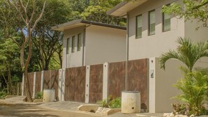 A modern two-story building with a beige exterior, green shutters, and a wooden fence. - Perfectly located in Playa Guiones. Walk to the beach, shops, restaurants & yoga (Nosara)
