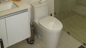 Un bagno con toilette, lavabo e box doccia in vetro.