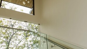 A modern staircase with glass railings and a ceiling light fixture with clear glass orbs. - Perfectly located in Playa Guiones. Walk to the beach, shops, restaurants & yoga (Nosara)