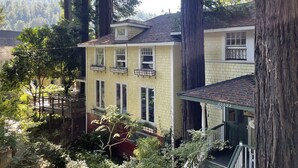 A two-story house with a yellow facade, multiple windows, and a porch. - Boho Manor Resort - Room B (Monte Rio)