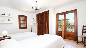 A room with two beds, a wooden door, a window, and a chandelier. - Plumera, Finca 5StarsHome Mallorca (Pollensa / Pollença)