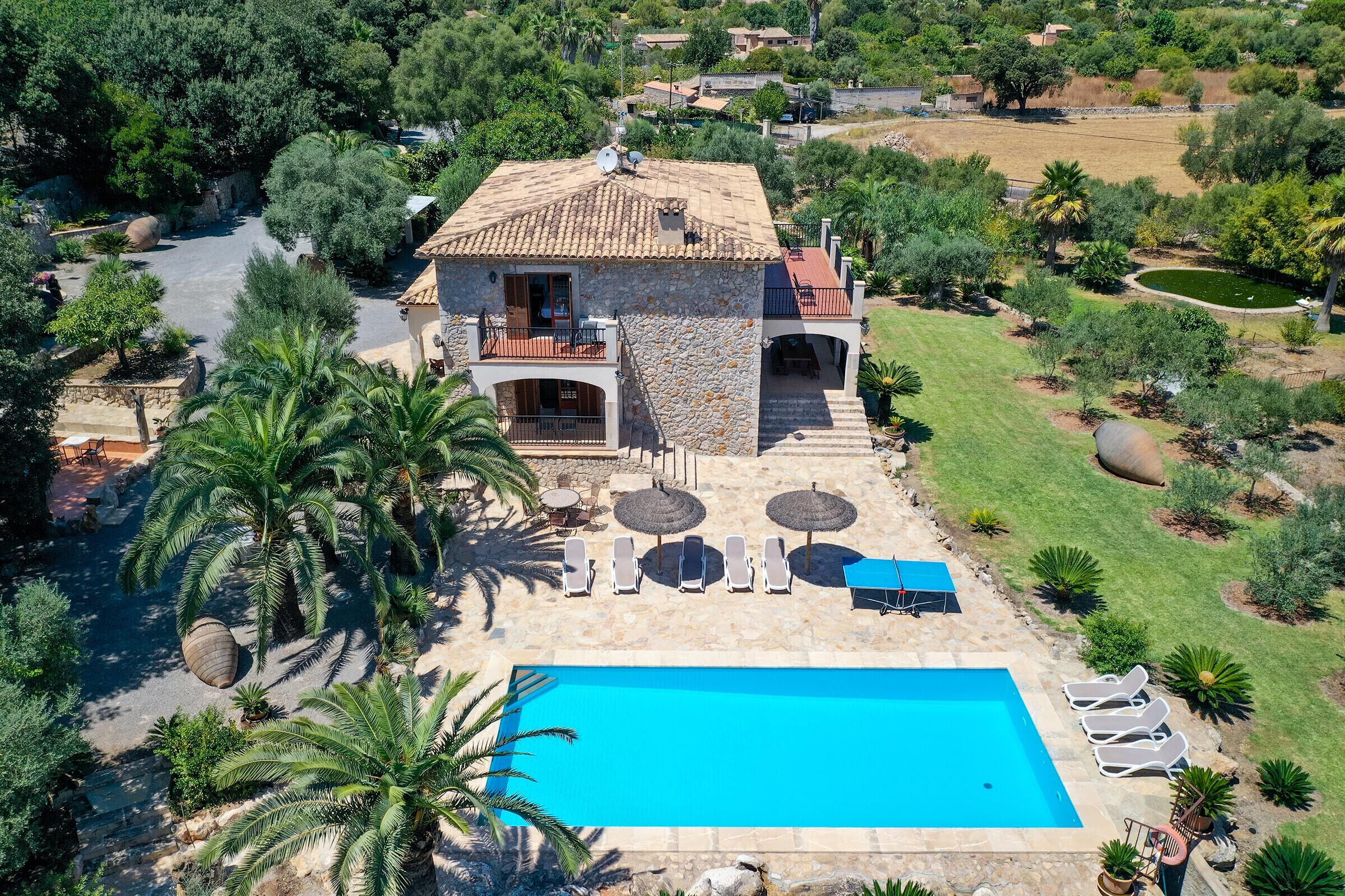 A villa with a swimming pool, surrounded by palm trees and a garden.