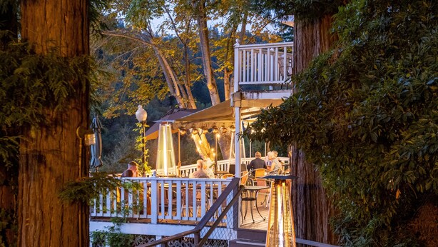 A wooden deck with outdoor seating, surrounded by trees and a railing. - Boho Manor Resort - Room 28 (Monte Rio)