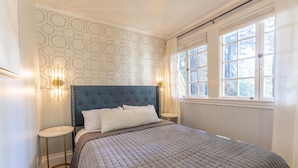 A neatly made bed with a quilted bedspread, a tufted headboard, and two bedside lamps. - Boho Manor Resort - Room 28 (Monte Rio)