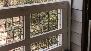 A wooden deck with a white railing and a window with metal bars.