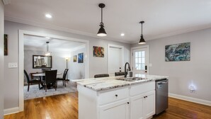 A modern kitchen with white cabinetry, a marble countertop, and a built-in dishwasher.