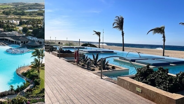 A resort with a large swimming pool, a beach area, and a wooden deck. - CONDO A BY TRVL2HM (Cabo San Lucas)