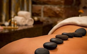 Une séance de massage thérapeutique utilisant des pierres chaudes sur le dos d’une personne.