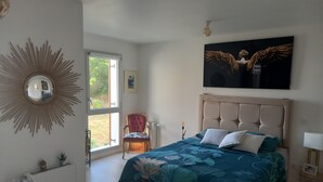 Een slaapkamer met een groot bed, een stoel, een radiator, een raam en een wandspiegel.