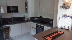 Een moderne keuken met witte kasten, een zwart aanrecht, een Siemens magnetron en een koffieapparaat.