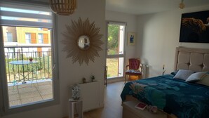 Een slaapkamer met een bed, een stoel, een tafeltje, een spiegel en een raam.