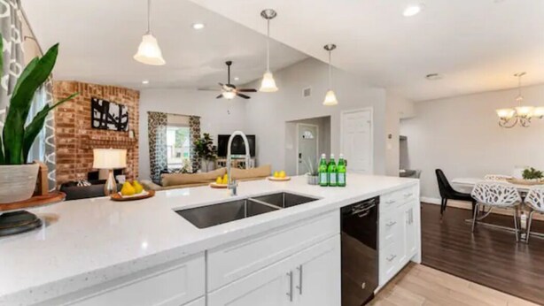 A modern kitchen with a central island, white cabinetry, and a dining area with a white table and chairs.