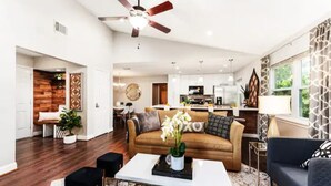A spacious living area with a brown sofa, a coffee table with a vase, and a ceiling fan.