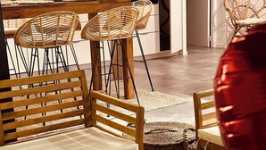 Un comedor con sillas de mimbre, un banco de madera y una mesa dispuesta para una comida.