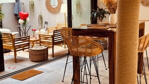 Un comedor moderno con mobiliario de mimbre, un espejo redondo y una planta en maceta.