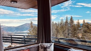 Ein gemütliches Zimmer mit Blick auf schneebedeckte Berge und Bäume.